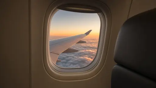 View of an airliner wing above clouds at sunrise through a cabin window